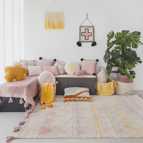 Interiors room setting with nude aztec rug and lots of nude, pink and ochre cushions and wall hangings